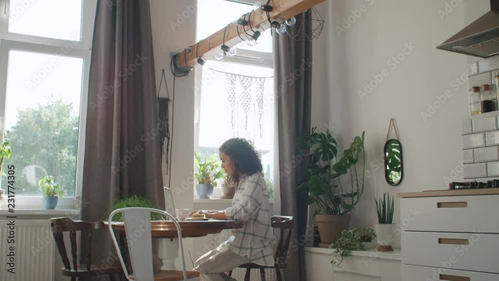Charming young woman typing on laptop computer at home.