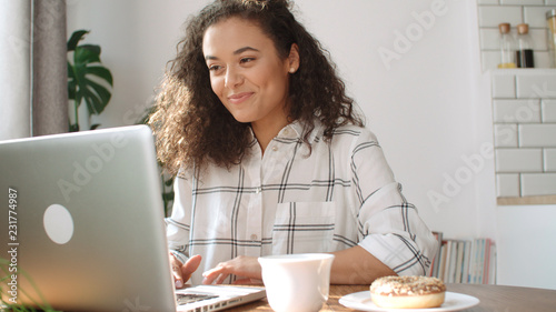 Charming young woman typing on laptop computer at home.