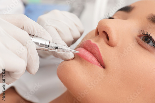 Fototapeta Naklejka Na Ścianę i Meble -  Young woman undergoing procedure of permanent lip makeup in tattoo salon, closeup