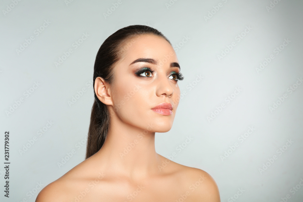 Portrait of young woman with eyelash extensions and makeup on light background. Space for text Portrait of young woman with eyelash extensions and makeup on light background. Space for text