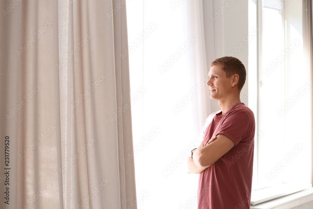 Mature man near window with open curtains at home. Space for text Mature man near window with open curtains at home. Space for text