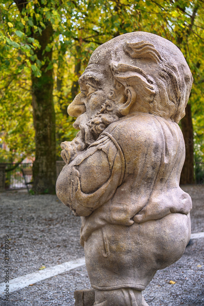 Stone statue of a dwarf. Marble sculpture of fairy gnome in Salzburg Mirabellgarten park, Salzburg, Austria