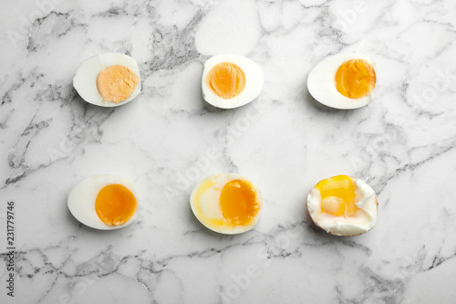 Various types of boiled eggs on marble background, flat lay. Cooking time