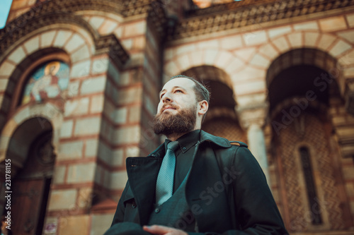 Handsome bearded man with mustache in front of church. Movember concept