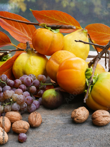 persimmons  grapes  figs and walnuts on a rustic wooden table with leaves  vertical