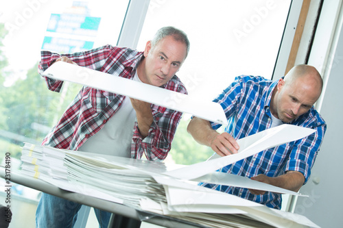 Fotografie Two workers looking through stack of papers