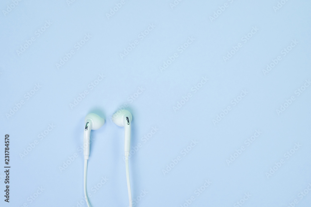 White Earphones or ear buds small talk on sweet blue colour pastel paper, top view, texture and background. music listening concept. White Earphones or ear buds small talk on sweet blue colour pastel paper, top view, texture and background. music listening concept.