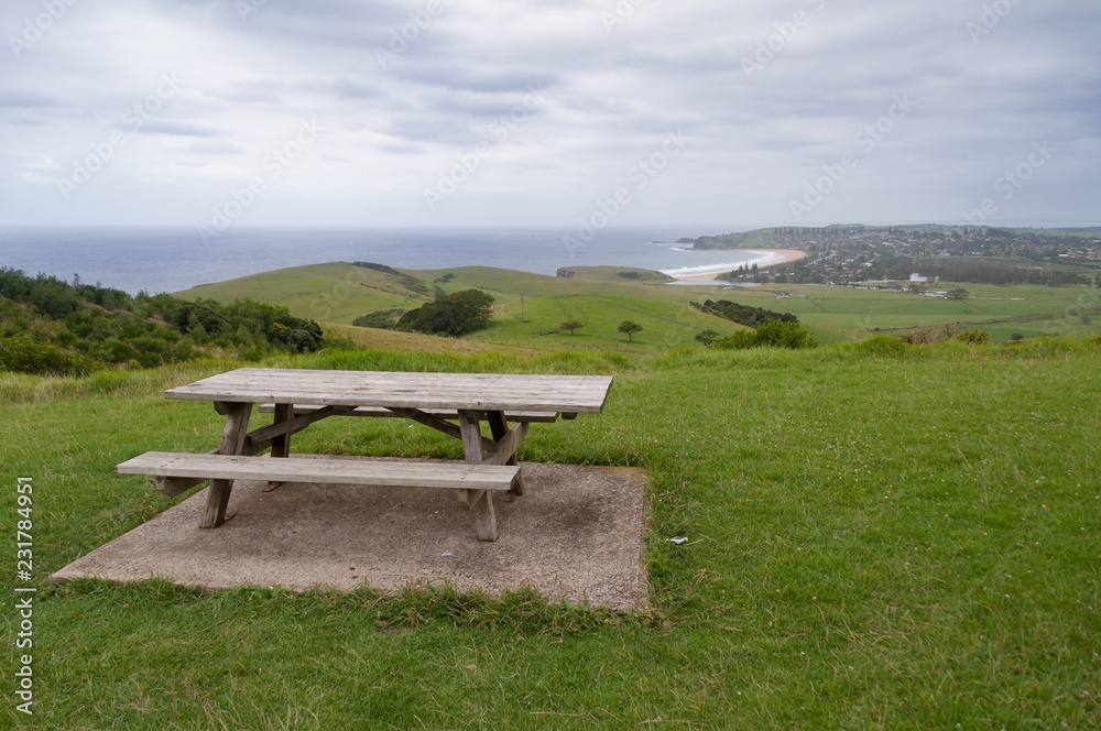 Picnic table with benches on green lawn with views of coastline Picnic table with benches on green lawn with views of coastline