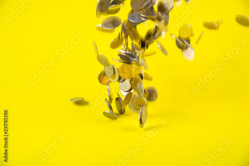Falling coins money on yellow background, business wealth concept.