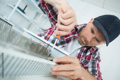 Man using screwdriver on electric heater