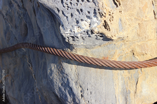 Rusty steel ship cable tied around rock boulder horizontal photo