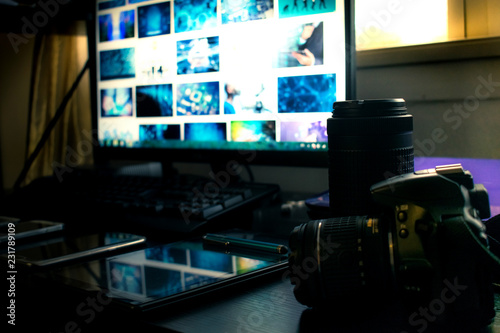 Closeup of black Modern Digital DSLR camera in Photography Workstation studio with Computer and monitor.