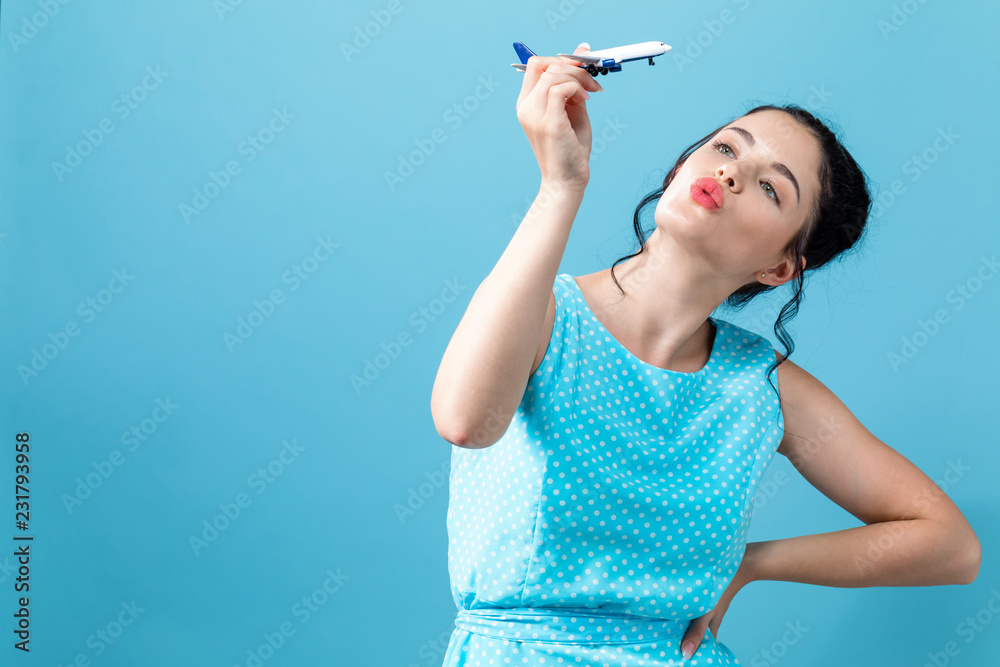 Young woman with toy airplane travel theme on a blue background Young woman with toy airplane travel theme on a blue background