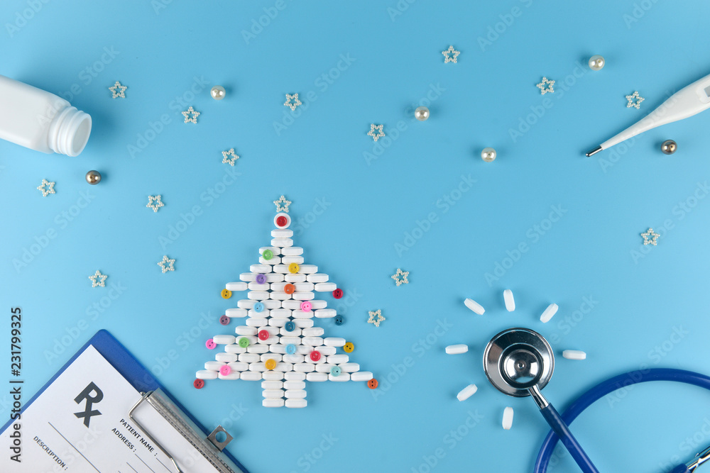 Obraz premium Medicine pills shape of christmas tree and others equipment of doctor on blue background. Concept christmas and new year.
