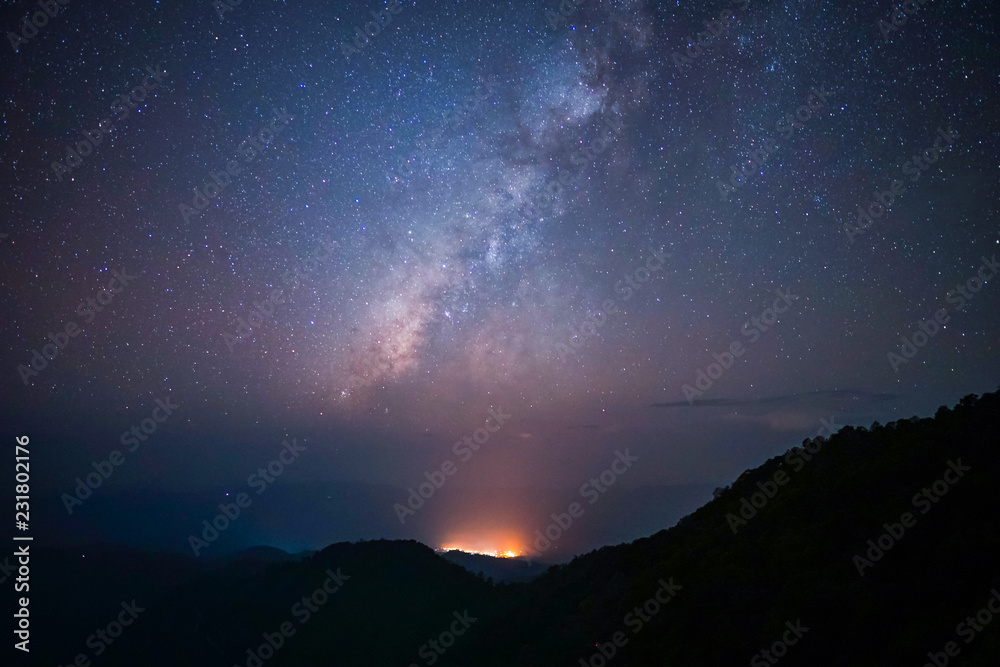 Milky way above the mountains peak with light from the village and noise Milky way above the mountains peak with light from the village and noise