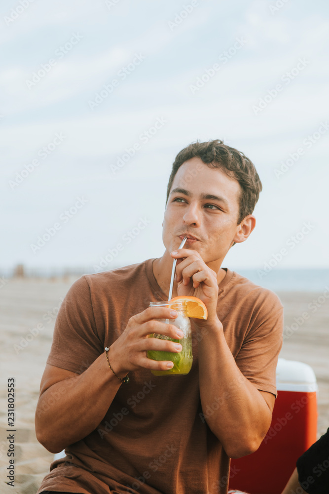 Fototapeta premium Man drinking a mojito at a beach party