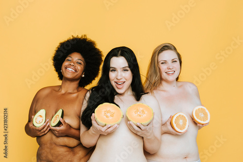 Diverse curvy nude women holding fruits over their breasts photo