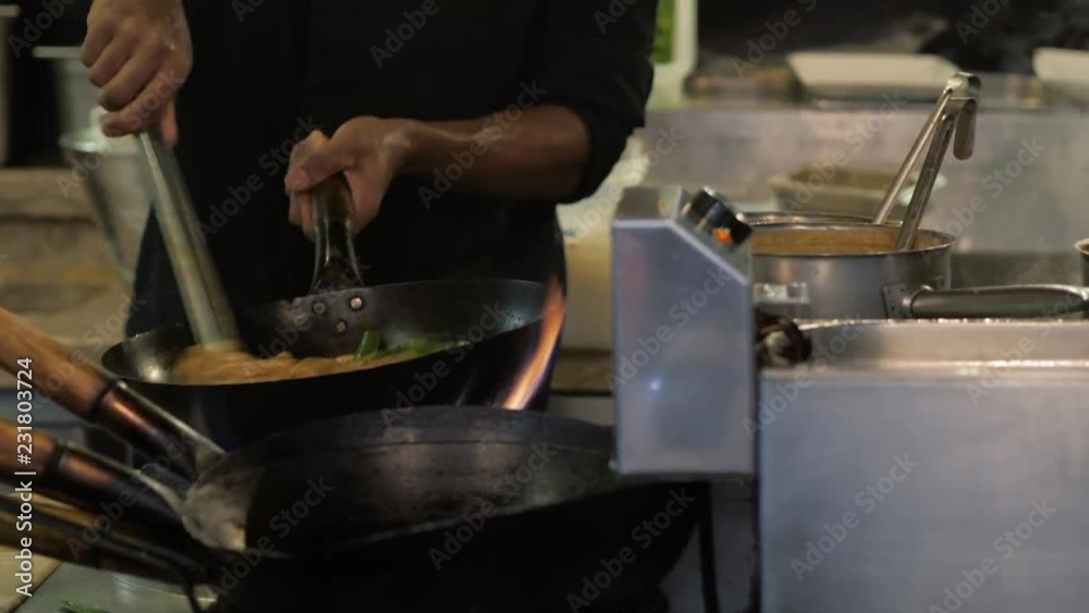 Chef is stirring vegetables in wok noodles fire flambe asia kitchen chinesse pan pasta seafood