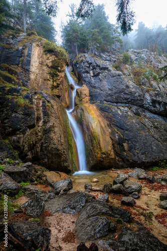 Waterfall in forest landscape long exposure flowing through trees and over rocks photo