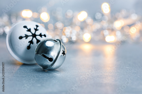 festive christmas jingle bells on grey background with blurred garland lights. macro view photo