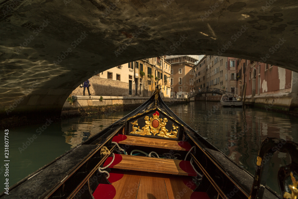 Inside gondola view as it going under the bridge on canals in Venice
