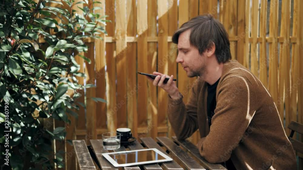 Handsome stylish man leaving message using voice recognition, speaking at smartphone in cafe bar drinking cocktail coffee message helper modern bar ai Handsome stylish man leaving message using voice recognition, speaking at smartphone in cafe bar drinking cocktail coffee message helper modern bar ai