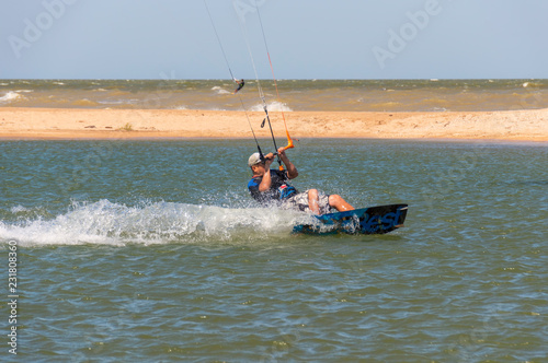 kitesurfing or kiteboarding, the athlete at the time of a jump above the surface of the water, against the background of a sea covered with waves and a sand spit