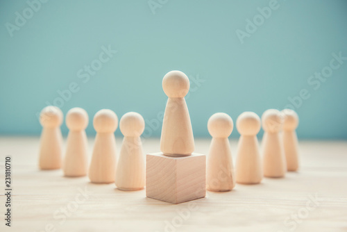 Leadership concept. Wood person model among people on blue background.