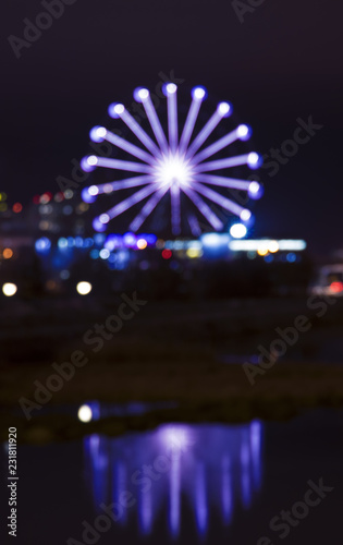 Vibrant blue colored ferris wheel bokeh reflected on water