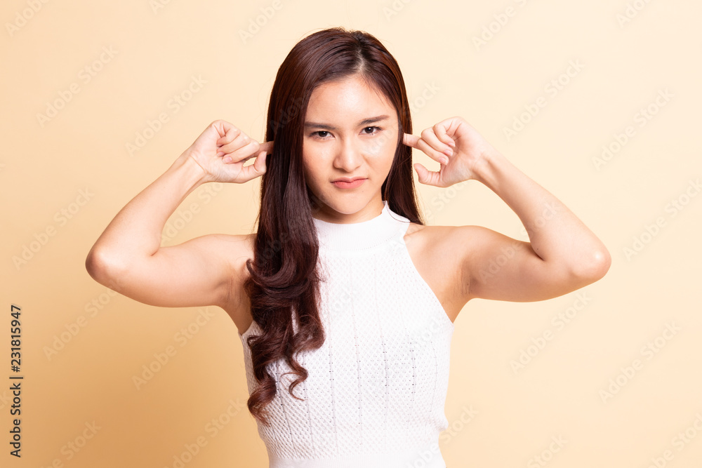 Young Asian woman block both ears with fingers.