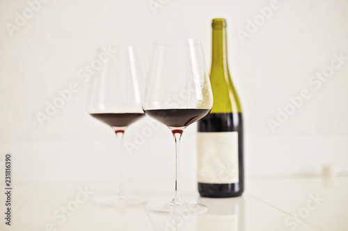 Red wine drinks in glasses with bottle on white background
