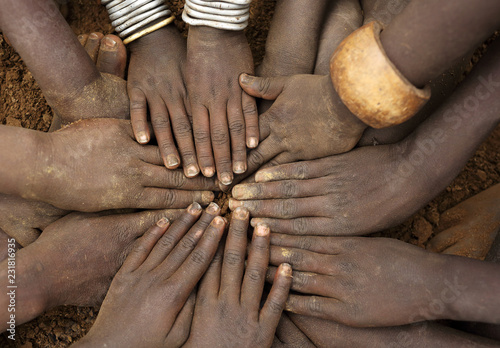 African ceremony of the Mursi tribe, close-up of hands of a group of children, Ethiopia photo