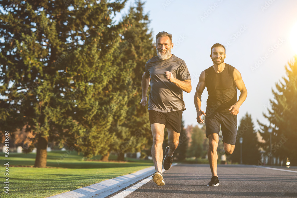 Fototapeta premium The happy father and a son running on a park road