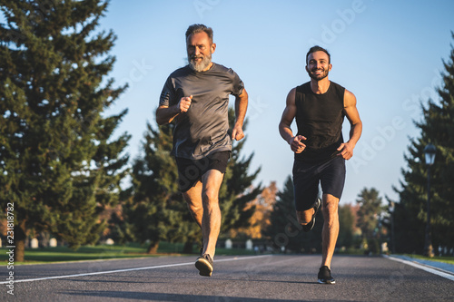 Fototapeta Naklejka Na Ścianę i Meble -  The father and a son running on the park road