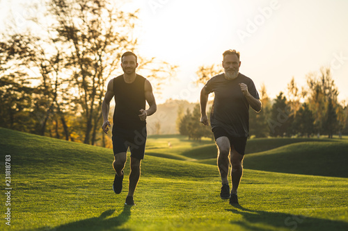 The happy father and a son running on the park grass