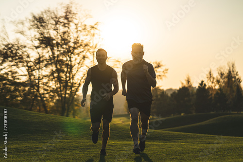 The happy father and a son running on a park grass on the sunset background