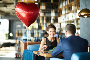 Happy young woman and her sweetheart enjoying lunch in restaurant on valentine day