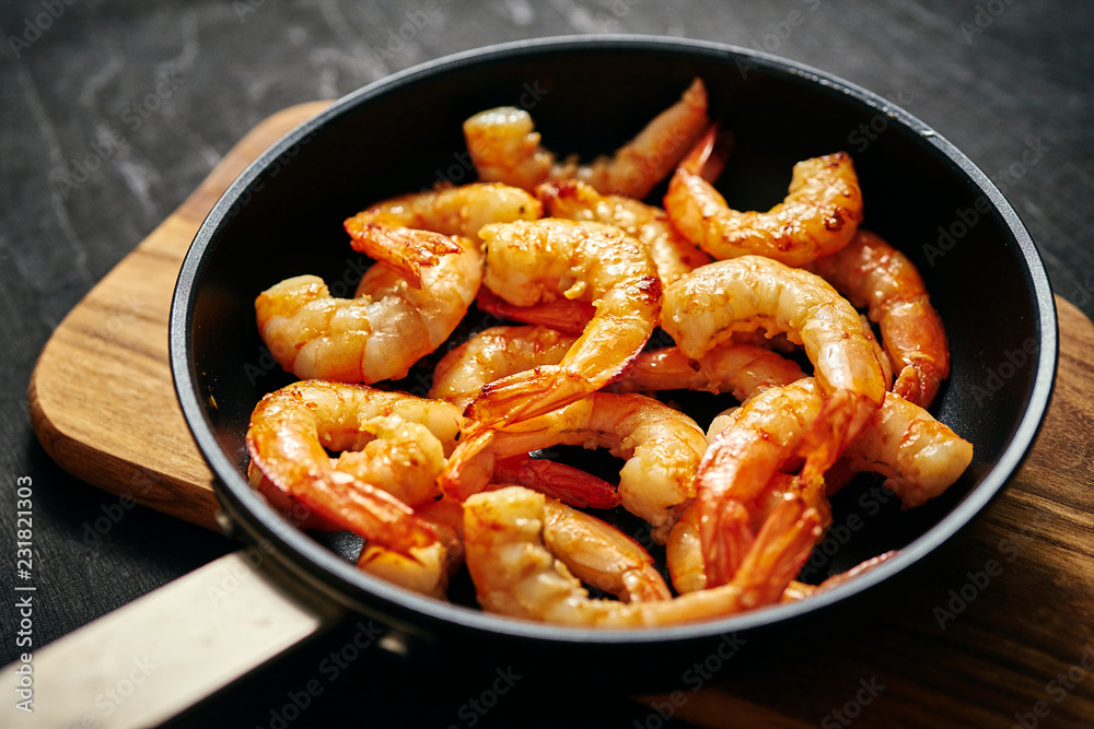 fresh delicious fried tiger prawns in a pan and wooden board fresh delicious fried tiger prawns in a pan and wooden board