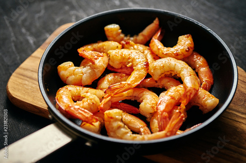 fresh delicious fried tiger prawns in a pan and wooden board