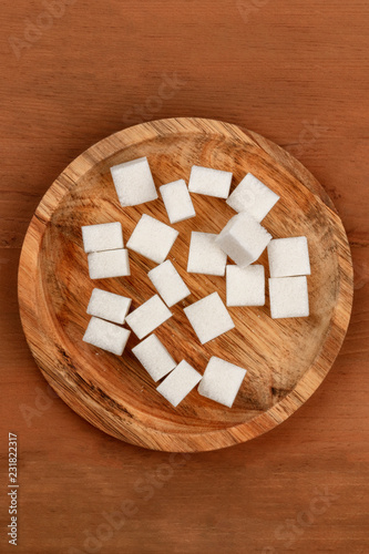 A photo of sugar cubes on a wooden plate, shot from the top on a dark rustic wooden background with a place for text