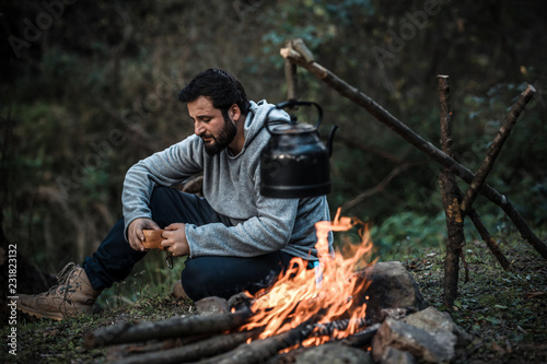 The Man hiking cooking a sausages on the campfire in forest, hike and people concept - happy relaxation camping. © sercansamanci