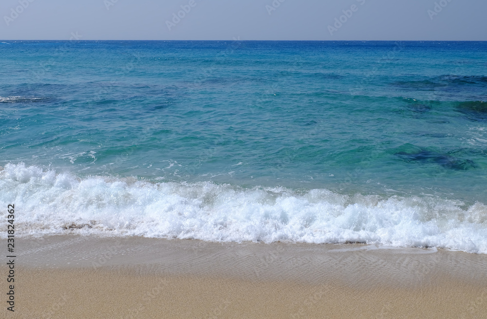 Tranquil image of Ocean in emerald and blue with waves and sand.