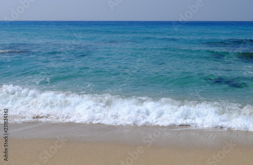 Tranquil image of Ocean in emerald and blue with waves and sand.