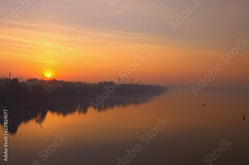 Landscape panorama of Dnipro River. Magnificent autumn sunrise in Kyiv. Foggy morning landscape. Beautiful city view with rising sun and fiery sky. Kyiv (Kiev), Ukraine © evgenij84