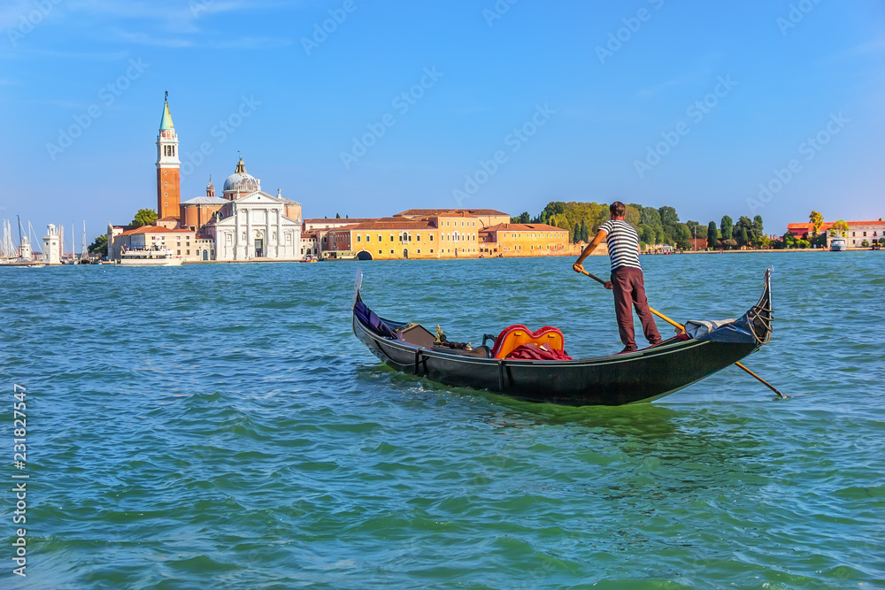 Obraz premium A gondolier sailing to San Giorgio Maggiore island in Venetian lagoon