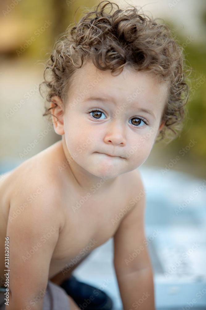 Beautiful baby with curly hair in the garden Beautiful baby with curly hair in the garden