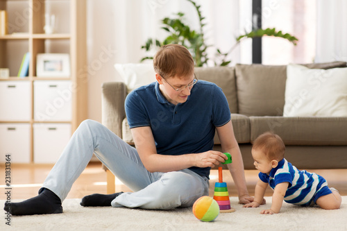 family, fatherhood and people concept - happy father with little baby son playing with toys at home