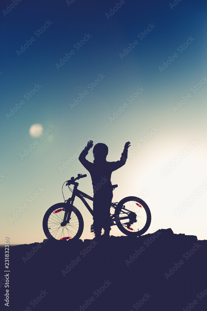 Silhouette of a little girl with a bicycle at sunset Silhouette of a little girl with a bicycle at sunset