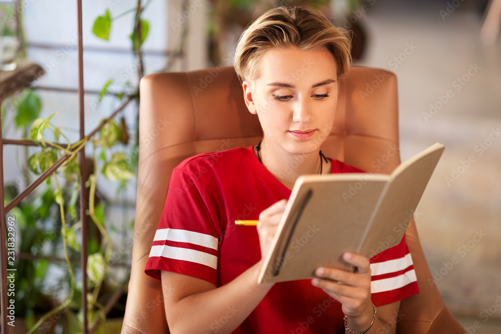 people, leisure and inspiration concept - young woman or teenage girl writing to notebook at cafe people, leisure and inspiration concept - young woman or teenage girl writing to notebook at cafe