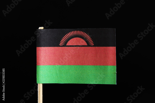 A original  flag of Malawi on toothpick on black background. Consists of a horizontal triband of black, red and green. Charged with a red rising sun with 31 rays centred on the black stripe photo